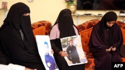 FILE - Family members hold pictures of a 20-year-old Libyan suspected to have been disappeared, at his home in the Sidi Essid district of the city of Tarhuna, southeast of the Libyan capital Tripoli, Nov. 10, 2020. 