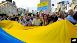Manifestantes desfilan con la bandera ucraniana en el Obelisco de Buenos Aires, Argentina, en protesta de la invasión de Rusia, el 6 de marzo de 2022.