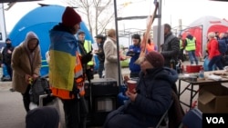 Already dazed refugees emerge from Ukraine into a winding path of tents and small marquees and they run a gauntlet of charity and hospitality, which at first adds to their disorientation, but as they relax it prompts smiles. (Jamie Dettmer/VOA)