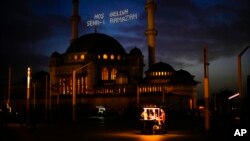 People buy roasted chestnuts next to Taksim mosque as the sun sets during the first day of the Muslim holy fasting month of Ramadan, in Istanbul, Turkey, April 2, 2022. Lights on top read in Turkish: 'Welcome Sehr-i Ramadan.'