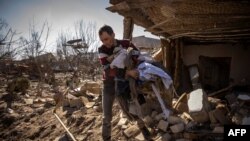 A man collects clothes from a damaged house in the city of Zhytomyr, northern Ukraine, on March 23, 2022. 