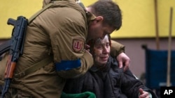 A soldier comforts Larysa Kolesnyk, 82, after she was evacuated from Irpin, on the outskirts of Kyiv, Ukraine, March 30, 2022.