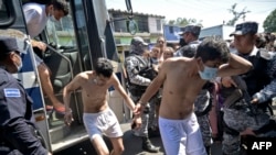 Hombres detenidos por asociación con las pandillas bajan de un autobús de la policía en San Salvador, El Salvador, el 31 de marzo de 2022.