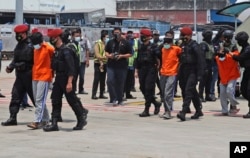 Polisi mengawal seorang terduga teroris setibanya di Bandara Internasional Soekarno-Hatta, Kamis, 18 Maret 2021. (Foto: AP)