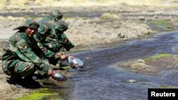 Soldados bolivianos lavan sus platos en un manantial en Silala, a unos 800 km (497 millas) al sur de La Paz, el 2 de septiembre de 2009.