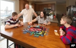 Nolan Balcitis, left, plays the board game Monopoly with his family at their home in Crown Point, Ind., on March 5, 2022. From left are Nolan, Bryan, Tabitha and Colin Balcitis. Nolan was diagnosed with Type 1 diabetes six months after a mild case of f COVID-19.