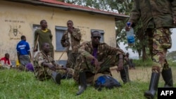 Des membres du groupe rebelle M23 assis dans le camp de réfugiés de Ramwanja, RDC, le 17 décembre 2014.