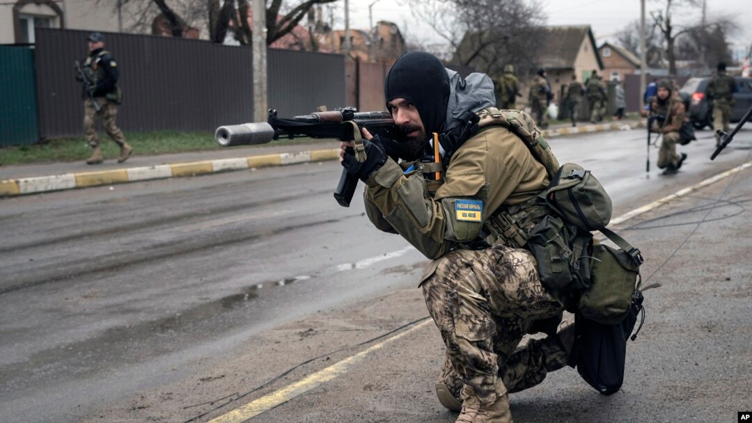 A Ukrainian serviceman secures the retreat of fellow soldiers who checked bodies lying on the street for booby traps in the formerly Russian-occupied Kyiv suburb of Bucha, April 2, 2022.