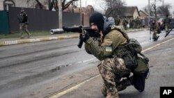 A Ukrainian serviceman secures the retreat of fellow soldiers who checked bodies lying on the street for booby traps in the formerly Russian-occupied Kyiv suburb of Bucha, April 2, 2022.