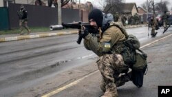A Ukrainian serviceman secures the retreat of fellow soldiers who checked bodies lying on the street for booby traps in the formerly Russian-occupied Kyiv suburb of Bucha, April 2, 2022.