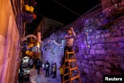 Seorang pria menggantung dekorasi jelang bulan suci Ramadhan di Kota Tua Yerusalem, 29 Maret 2022. (REUTERS/Ammar Awad)