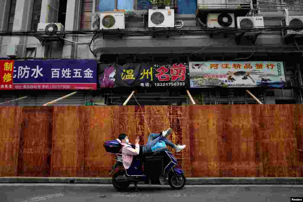 A man uses a cellphone while resting on a scooter in front of barricades of a sealed-off area, following the COVID-19 outbreak in Shanghai, China.