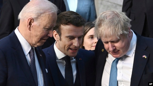 President Joe Biden, left, talks with French President Emmanuel Macron and British Prime Minister Boris Johnson, right, as they arrive at NATO Headquarters in Brussels, March 24, 2022.
