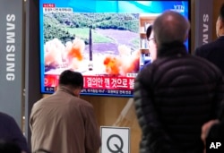 People watch a TV showing a file image of North Korea's missile launch during a news program at the Seoul Railway Station in Seoul, South Korea, March 24, 2022.