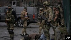 Ukrainian servicemen stand while checking bodies of dead civilians for booby traps in the formerly Russian-occupied Kyiv suburb of Bucha, Ukraine, April 2, 2022.
