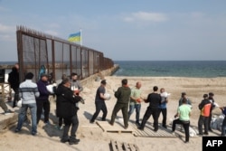 Local residents carry bags filled with sand as they build a barricade for a checkpoint in Odesa on March 25, 2022, amid the Russian invasion of Ukraine.