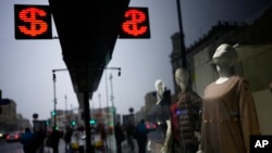 People walk past a currency exchange office screen displaying the exchange rates of the US dollar and euro to Russian rubles in Moscow's downtown, March 29, 2022.