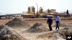 Rod Colwell, CEO Controlled Thermal Resources, kanan, berjalan di sepanjang pot lumpur panas bumi di dekat pantai Laut Salton, tempat perusahaan menambang lithium, di Niland, California, Kamis, 15 Juli 2021. (Foto: AP)