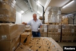 FILE - Shaun Mcvey, marketing manager at Vergenoegd Low Wine Estate, stands amongst cases of their Runner Duck wines at the estate near Cape Town, South Africa, Feb. 3, 2021.