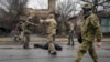 Ukrainian servicemen attach a cable to the body of a civilian while checking for booby traps in the formerly Russian-occupied Kyiv suburb of Bucha, April 2, 2022.