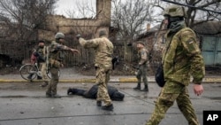 Ukrainian servicemen attach a cable to the body of a civilian while checking for booby traps in the formerly Russian-occupied Kyiv suburb of Bucha, April 2, 2022.