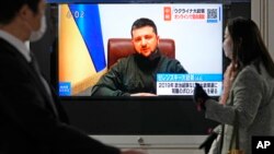 日本民眾走過街頭正在播放烏克蘭總統澤連斯基對日本國會在線演講實況的電視屏幕。（2022年3月23日）