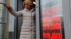 FILE - In this Feb. 24, 2022, photo, a woman leaves an exchange office, where a screen showing the currency exchange rates of the U.S. dollar and euro to Russian rubles is displayed, in Moscow.