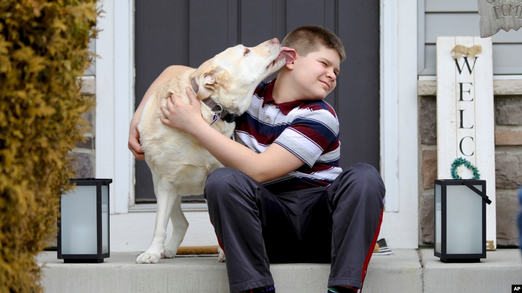 Nolan Balcitis, 12, sits with his dog, Callie, in front of his family's home in Crown Point, Ind., on March 4, 2022. Nolan was diagnosed with Type 1 diabetes six months after a mild case of COVID-19. (AP Photo/Teresa Crawford)