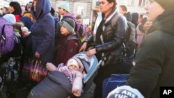 Refugiados con niños esperan un transporte después de huir de la guerra desde la vecina Ucrania en una estación de tren en Przemysl, Polonia, el jueves 24 de marzo de 2022. (Foto AP/Sergei Grits)