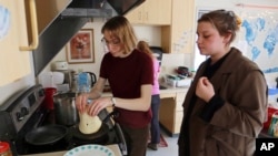 Students Sophia Pavlenko, left, of Russia, and Masha Novikova, of Ukraine, prepare blini, the Eastern European-style crepes, to sell to fellow students in a dorm at the United World College, March 12, 2022, in Montezuma, N.M.