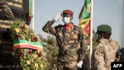 Le président malien de transition, le colonel Assimi Goïta (à droite) regarde après avoir déposé une gerbe sur le monument aux morts, lors de la cérémonie célébrant la fête nationale de l'armée, à Kati, le 20 janvier 2022. (Photo par FLORENT VERGNES / AFP ) 