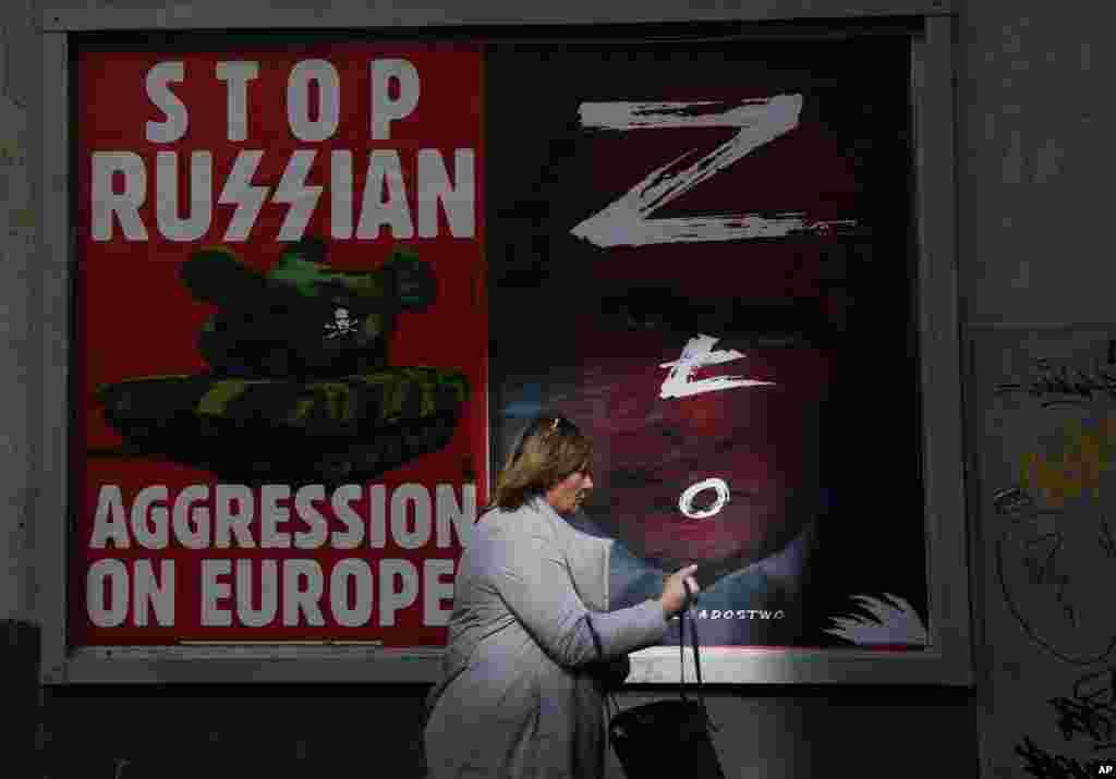 A woman walks past a wall with posters showing Russian President Vladimir Putin, in Warsaw, Poland.