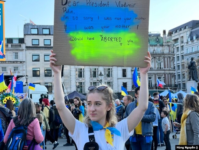Cô gái này giơ cao những dòng chữ ‘Thưa Tổng thống Vladimir Putin, Tôi xin lỗi tôi không phải là mẹ ông. Nếu tôi là mẹ ông tôi đã PHÁ THAI ông’.