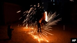 A boy swings fireworks during the Muslim holy fasting month of Ramadan, in Gaza City, April 2, 2022.