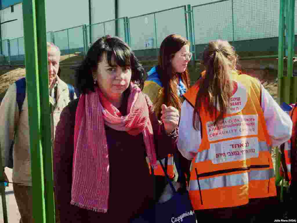 Refugiada ucraniana llega a Medyka. A su derecha, voluntarios se organizan para asistir a los refugiados. Muchos de los refugiados cruzan la frontera tras días de viaje.&nbsp;