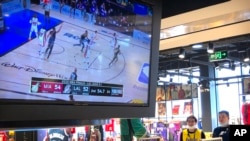FILE - Employees watch a live broadcast of Game 5 of the NBA Finals at an NBA store in Beijing, China, Oct. 10, 2020. 