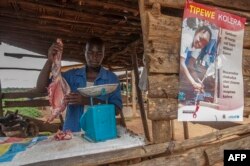 Seorang tukang daging menyiapkan daging kambing di samping poster UNICEF yang menyerukan orang-orang untuk mengambil tindakan pencegahan untuk melindungi diri dari kolera, di Likuni, di luar Lilongwe, Malawi, 27 Januari 2018. (Foto: AFP)