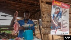 FILE - A butcher prepares goat meat next to a UNICEF poster calling on people to take precautions to protect themselves against cholera, in Likuni, outside Lilongwe, Malawi, Jan. 27, 2018. 