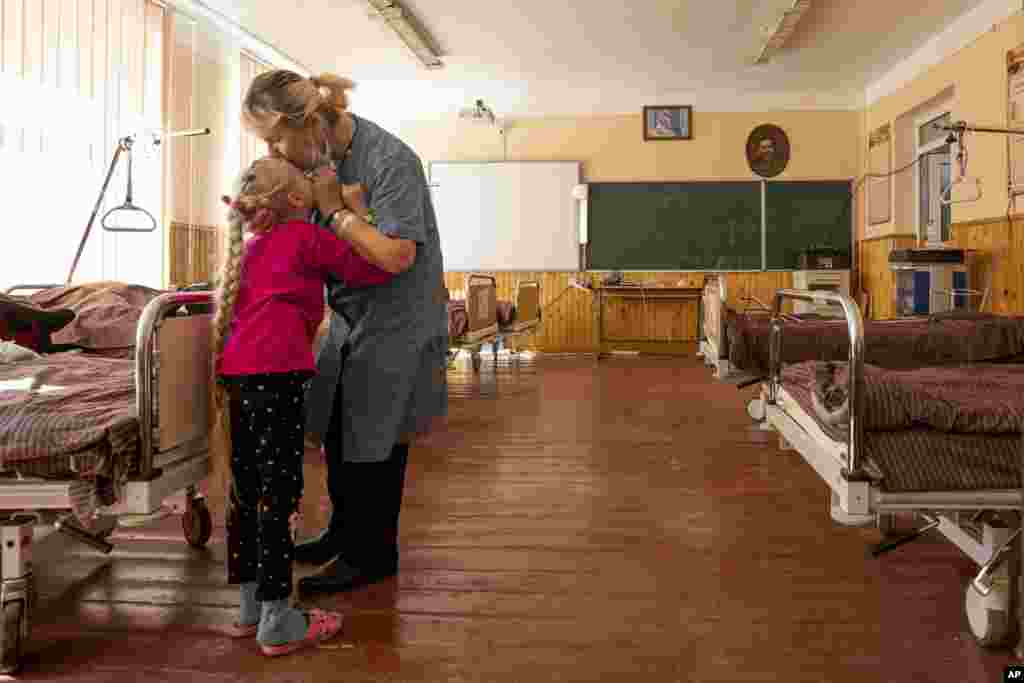 Nadia kisses her 10-year-old granddaughter Zlata Moiseinko, suffering from a chronic heart condition, as she receives treatment at a schoolhouse that has been turned into a field hospital in Mostyska, western Ukraine.