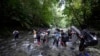Migrantes -en su mayoría haitianos- cruzan el río Acandi en su viaje hacia el norte, en Colombia, el 15 de septiembre de 2021. 