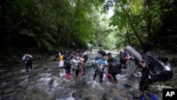 Migrantes -en su mayoría haitianos- cruzan el río Acandi en su viaje hacia el norte, en Colombia, el 15 de septiembre de 2021. 