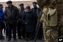 Displaced people wait in line outside the District Department of the State Migration Service to receive food and a place to sleep, in Brovary, on the outskirts of Kyiv, Ukraine, March 29, 2022.