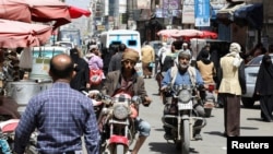 Muškarci se voze na motorima dok drugi hodaju ulicom satima prije nego što dvomjesečno primirje stupi na snagu, u Sani, Jemen, 2. aprila 2022.