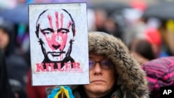 A demonstrator holds a placard of Russian President Vladimir Putin covered with a blood-smeared hand and a ribbon in the colors of the Ukraine flag during a rally in Budapest, Hungary, April 2, 2022, ahead of Sunday's election.