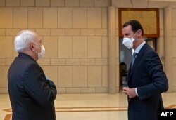 FILE - A picture released by the official Syrian Arab News Agency on April 20, 2020, shows President Bashar Al-Assad, right, meeting Iranian Foreign Minister Mohammad Javad Zarif in the Syrian capital Damascus.