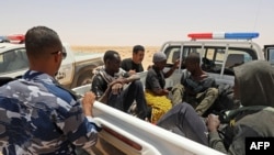FILE - Libyan border guards rescue migrants from sub-Saharan African countries who claim to have been abandoned in the desert by Tunisian authorities without water or shelter, in an uninhabited area near the border town of Al-Assah on July 16, 2023.