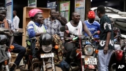 Drivers of motorcycle taxis, known locally as boda-bodas, ride with passengers on a street of Kampala, Uganda, on July 18, 2024.