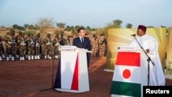 FILE - French President Emmanuel Macron and Niger President Mahamadou Issoufou pay homage to Niger soldiers killed in an attack on a military camp, in Niamey, Niger, Dec. 22, 2019. At least 89 died in another attack Jan. 9 in Chinagodrar..