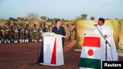 FILE - French President Emmanuel Macron and Niger President Mahamadou Issoufou pay homage to Niger soldiers killed in an attack on a military camp, in Niamey, Niger, Dec. 22, 2019. At least 89 died in another attack Jan. 9 in Chinagodrar..