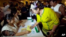 A volunteer clad in Shan ethnic traditional costume fills in a ballot paper during a rehearsal presentation for the upcoming general election Friday, May 15, 2015, in Yangon, Myanmar. (AP Photo/Khin Maung Win)